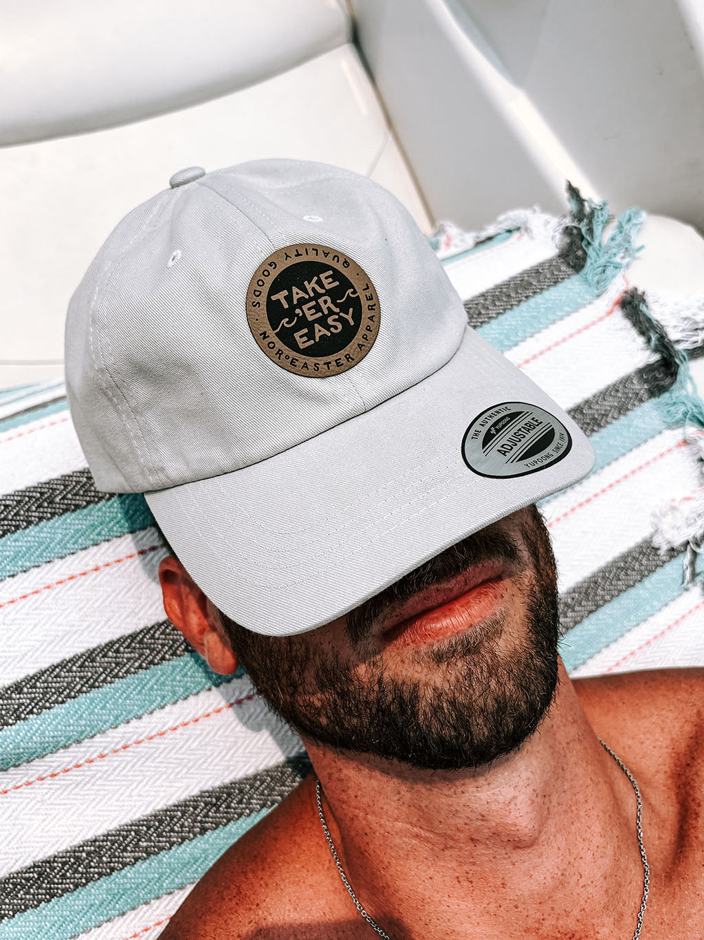 man on a boat sleeping with a Nor'easter Apparel Take Er Easy hat covering his face. Front view.
