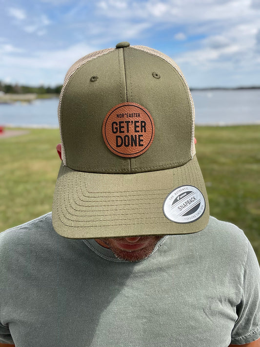 black nor'easter hat front view with a faux leather patch saying get'er done