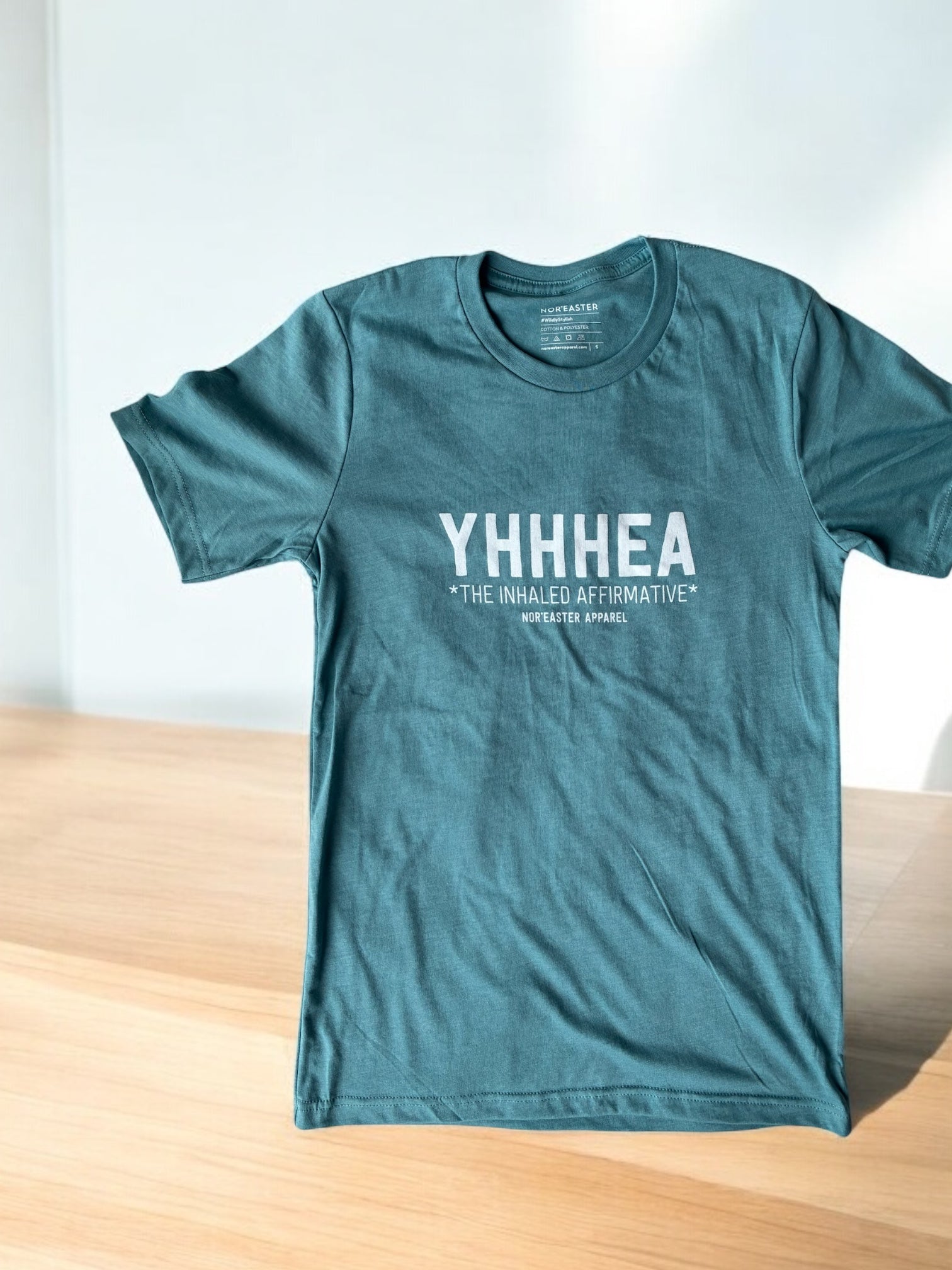 Teal t-shirt with white text on a wooden surface