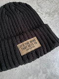 Black beanie with a leather patch on a gray surface