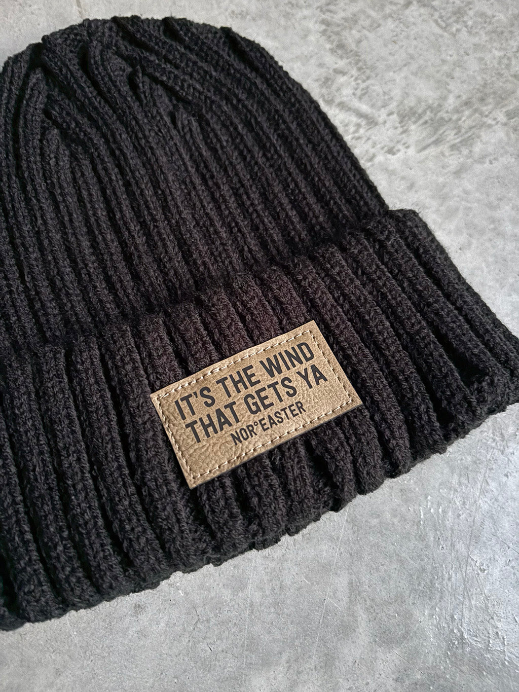 Black beanie with a leather patch on a gray surface