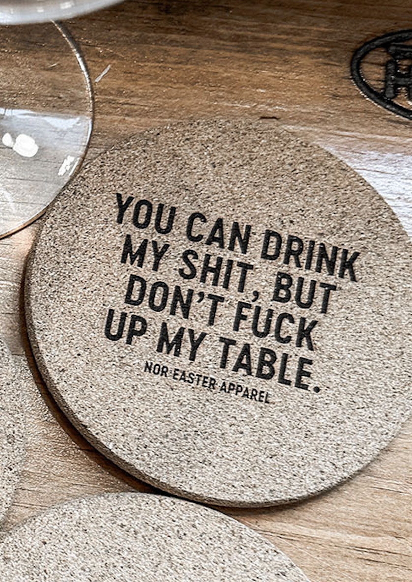 Coaster with humorous text on a wooden surface