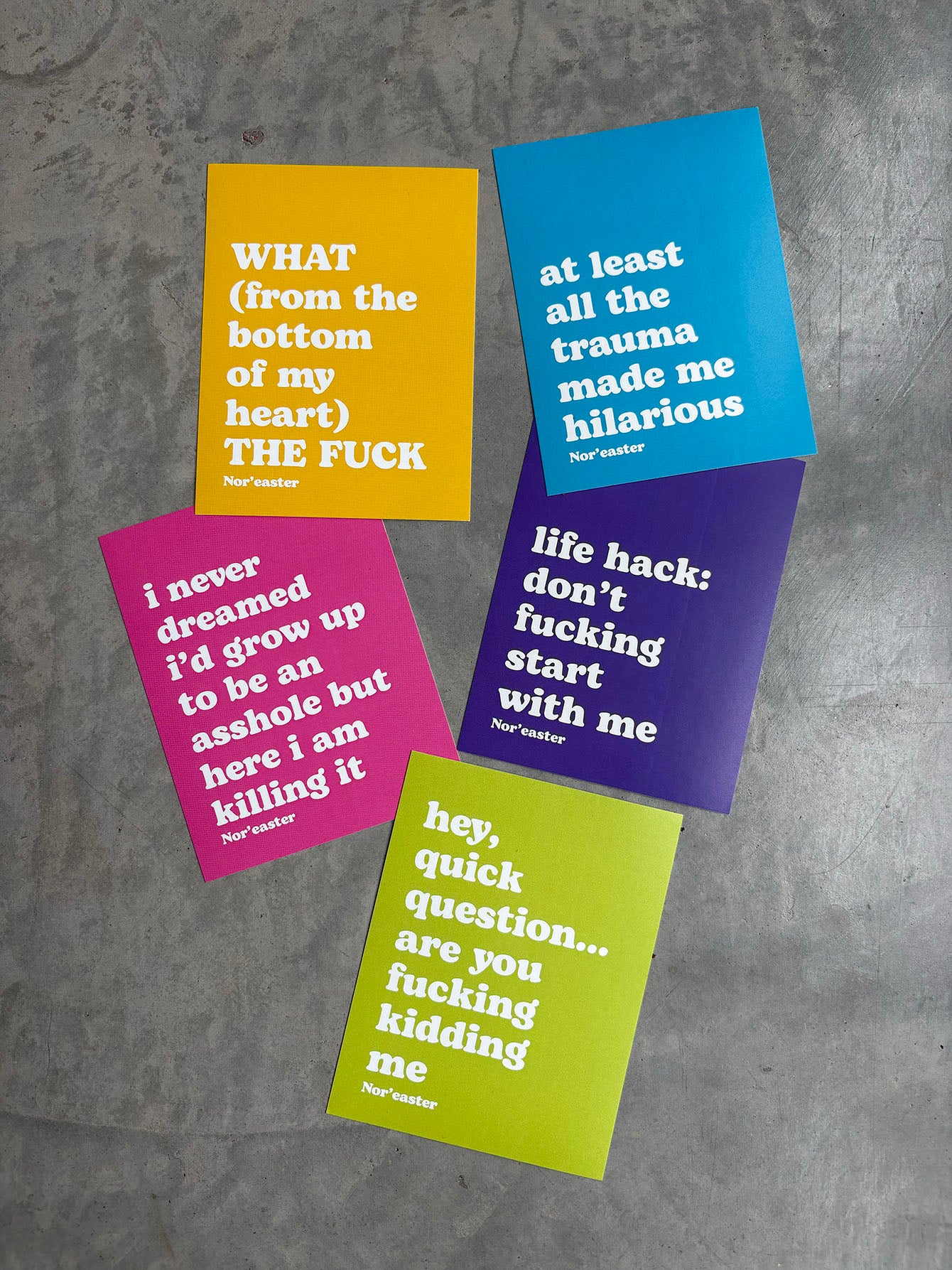 Five colorful cards with humorous text on a gray surface