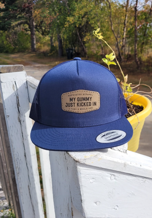 Navy Trucker Hat Gummy Kicked In front view on a white railing
